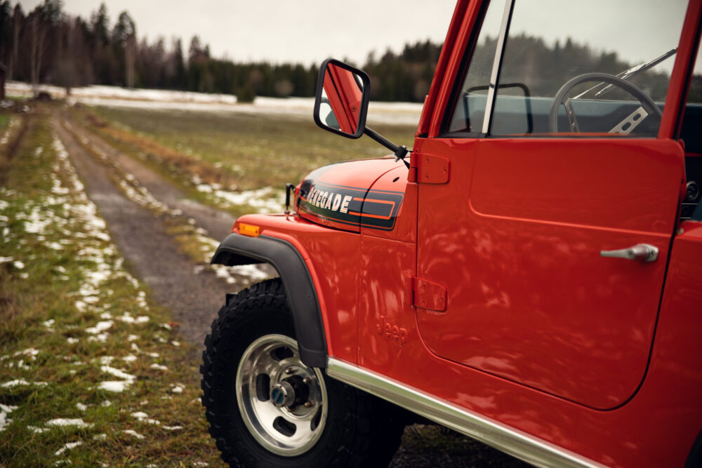 Red Jeep Renegade on snow-patched country road