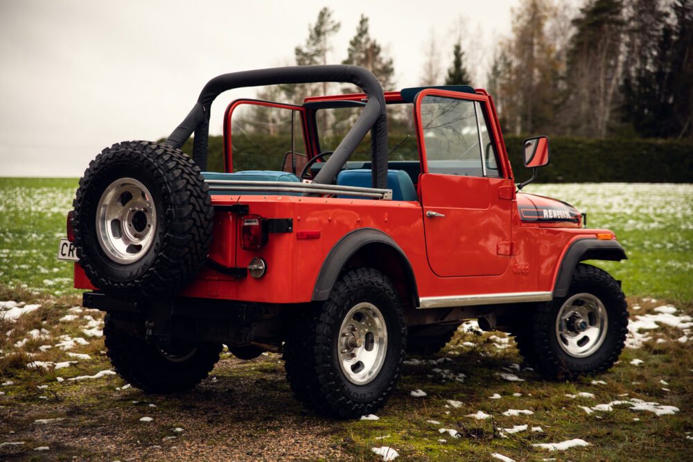 Red Jeep Wrangler parked on snowy grass