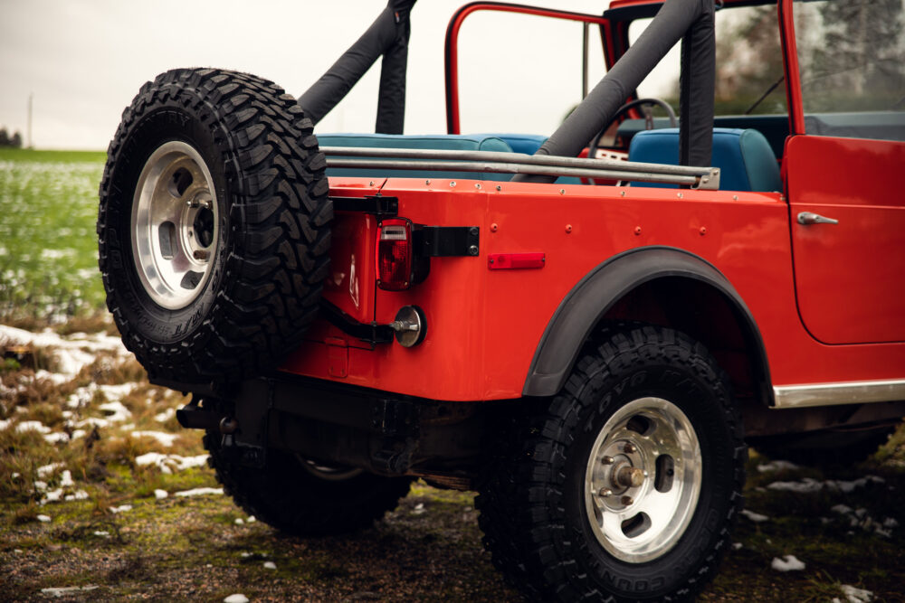 Red off-road vehicle with spare tire in snowy field