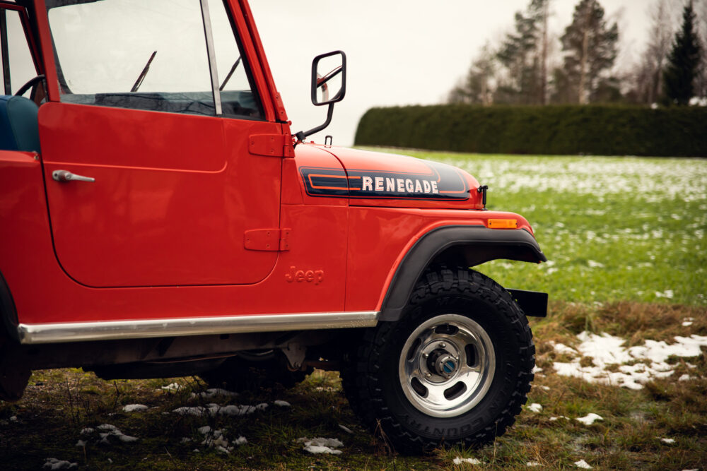 Red Jeep Renegade parked on grass with snow patches