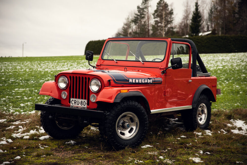 Red vintage jeep in snowy grass field