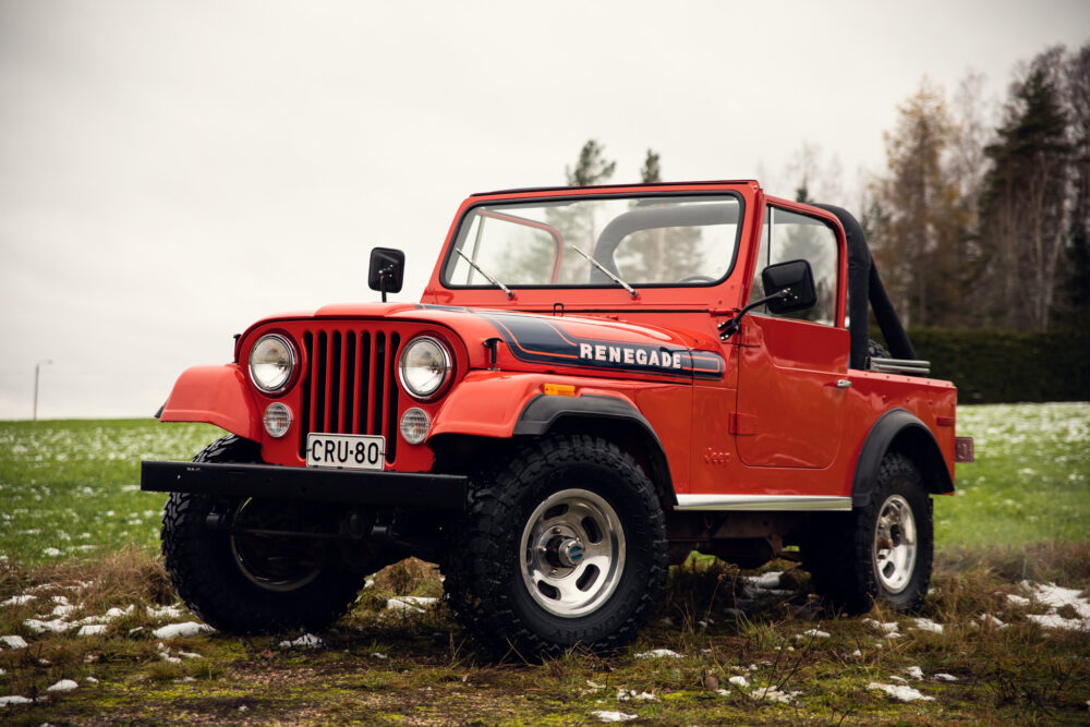 Red vintage Jeep Renegade on snowy grass field