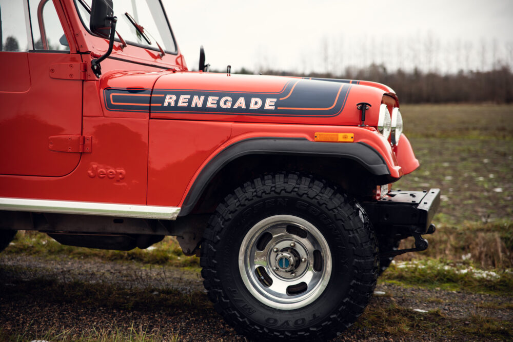 Red Jeep Renegade side view on muddy field