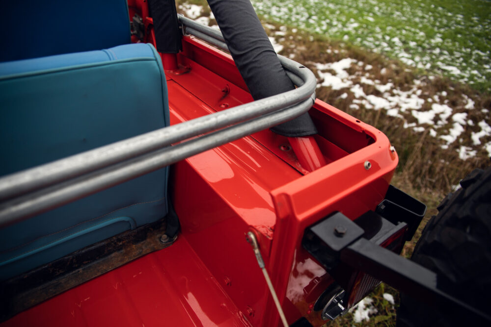 Close-up of red jeep's open side door in field