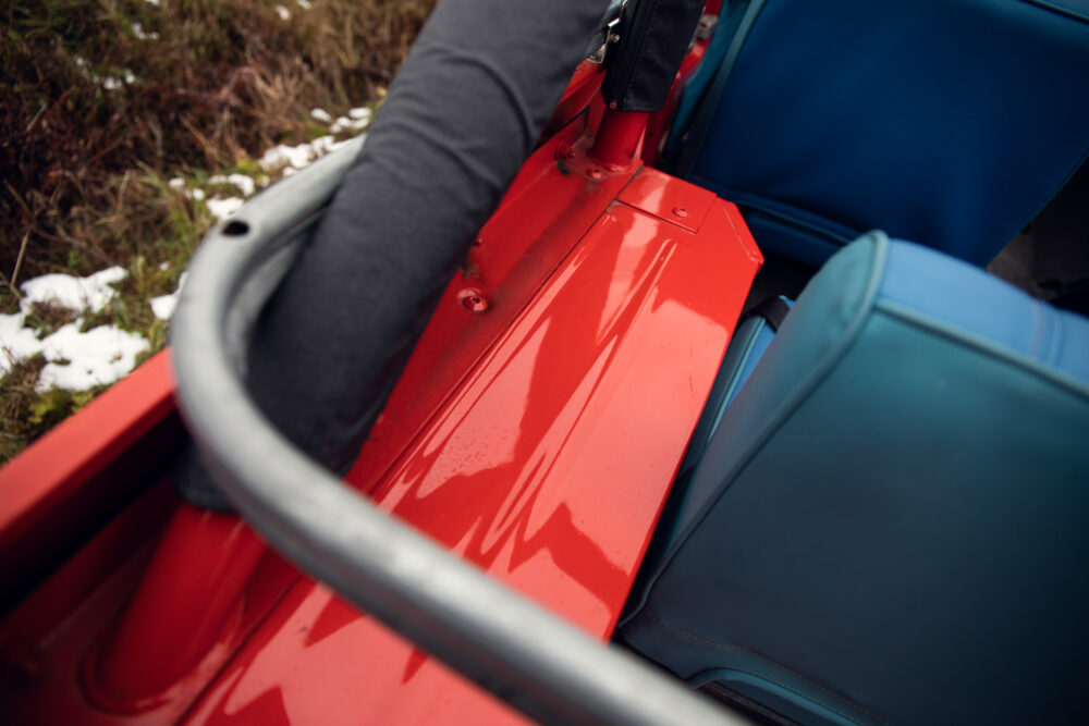 Colorful luggage loaded in red car trunk, snow visible