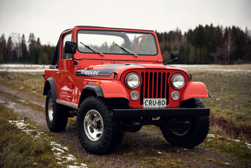 Red Jeep Renegade on rural trail with snowy patches