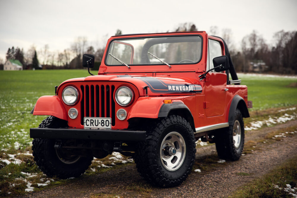 Vintage red Jeep Renegade on grassy field