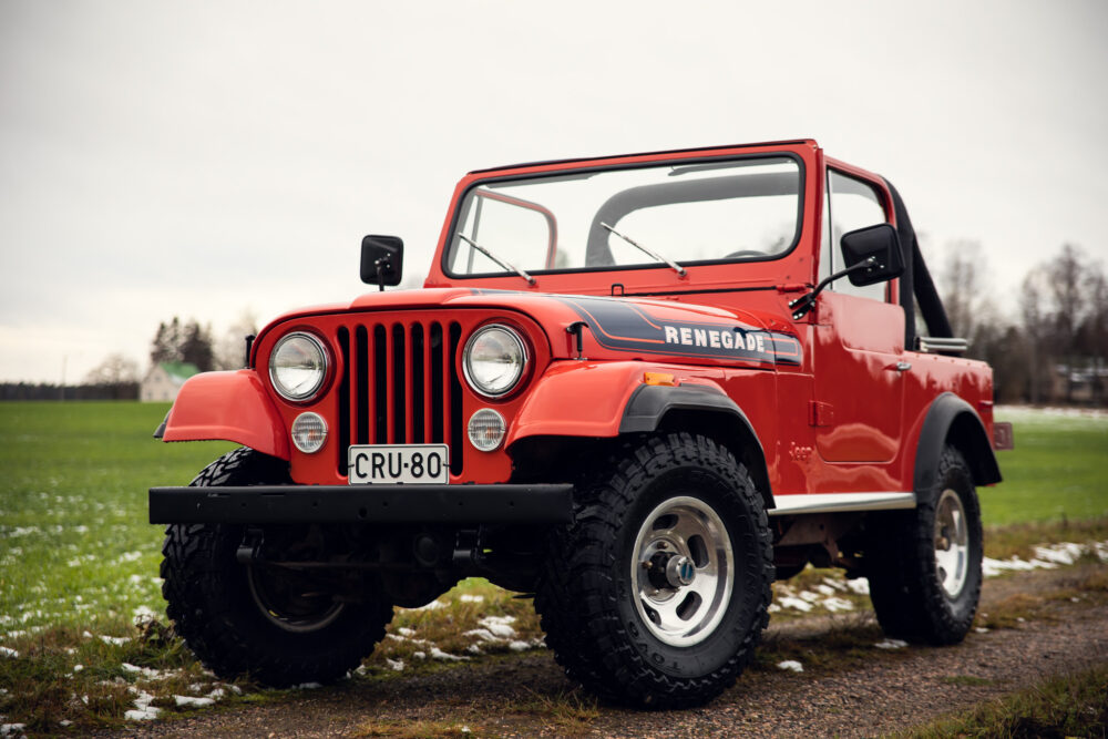 Red vintage Jeep Renegade on grassy field