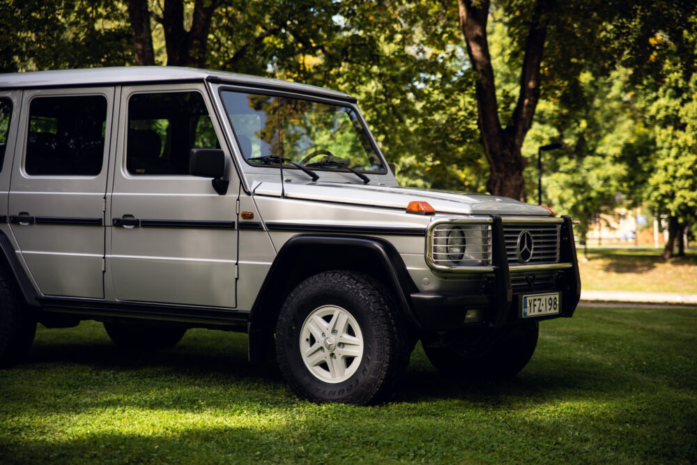 Silver SUV parked under trees in sunny park