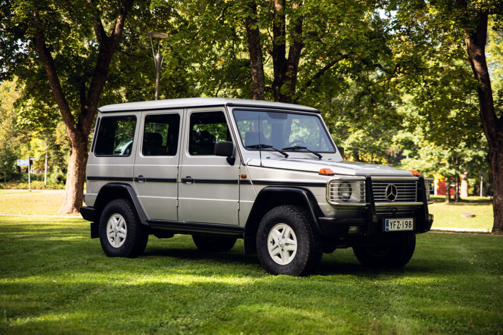 Silver SUV parked on grass amidst trees