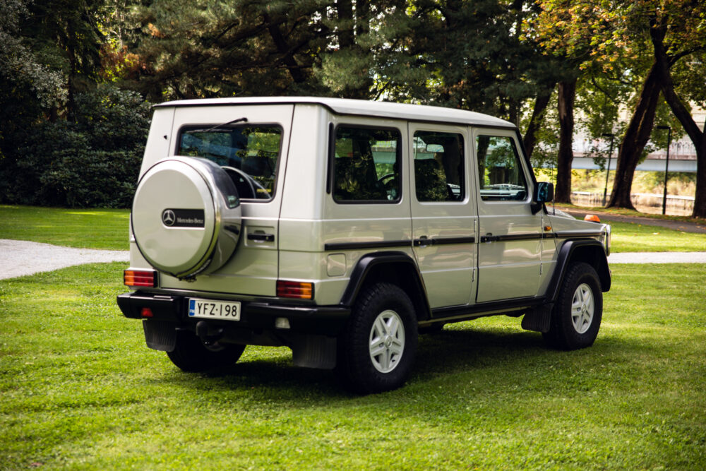 Green Mercedes SUV parked in lush park setting