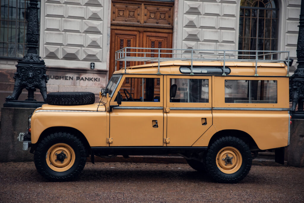 Vintage yellow Land Rover parked by building