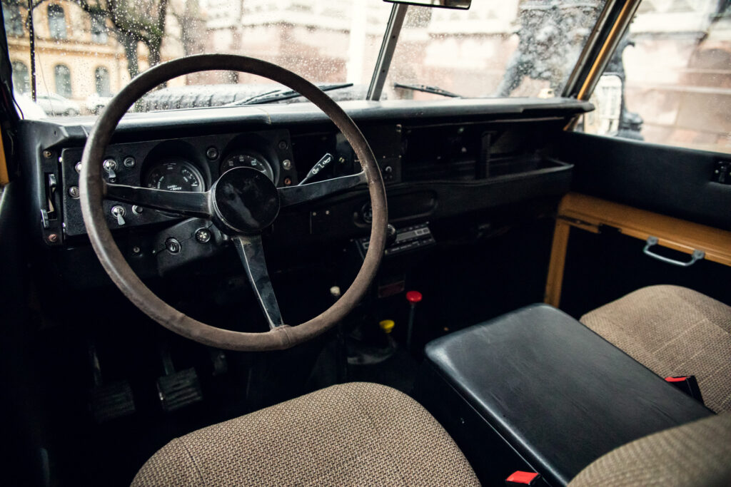 Vintage car interior with steering wheel and rainy window