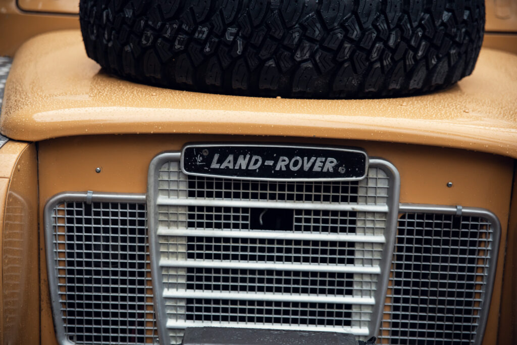 Wet yellow Land Rover front grille and tire