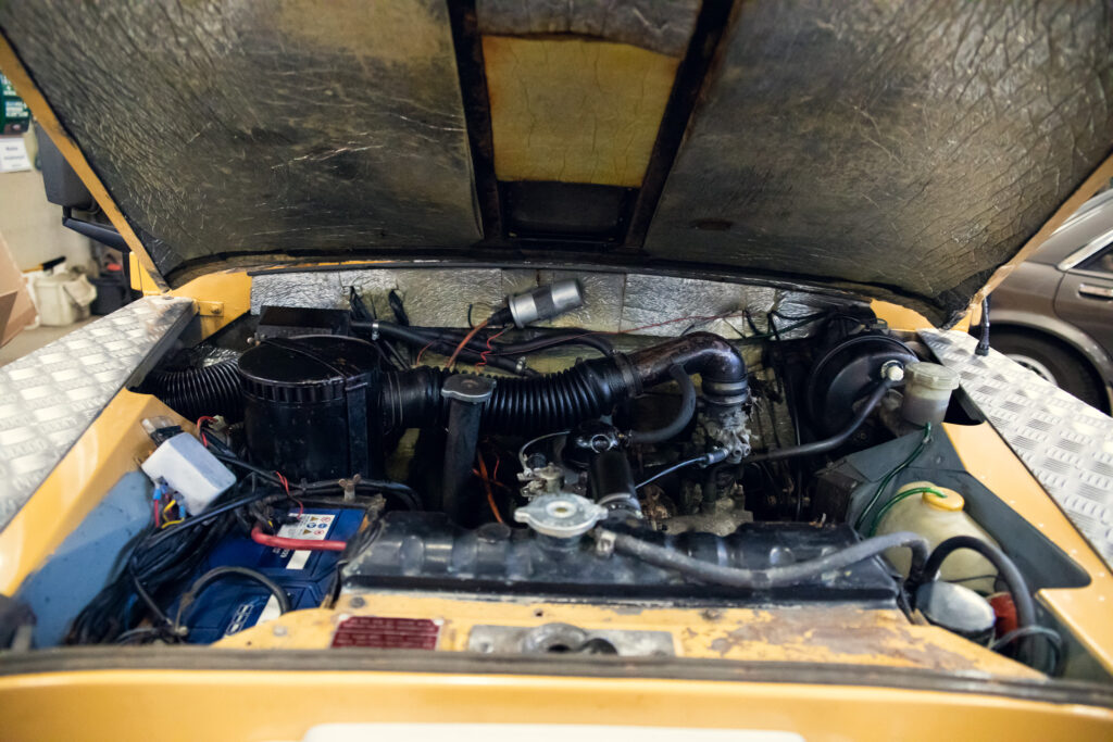 Open engine hood of a vintage yellow car