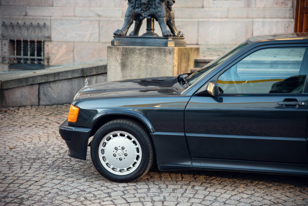 Vintage black car parked near bronze lion statue