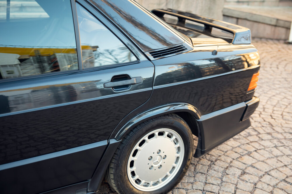 Vintage black Mercedes-Benz car parked on cobblestone street.