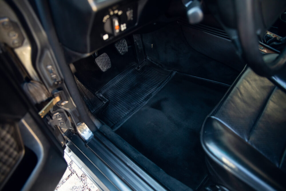 Interior view of a car showing pedals and floor mats