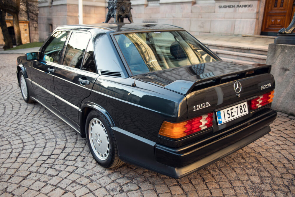 Classic black Mercedes 190E parked near historic building