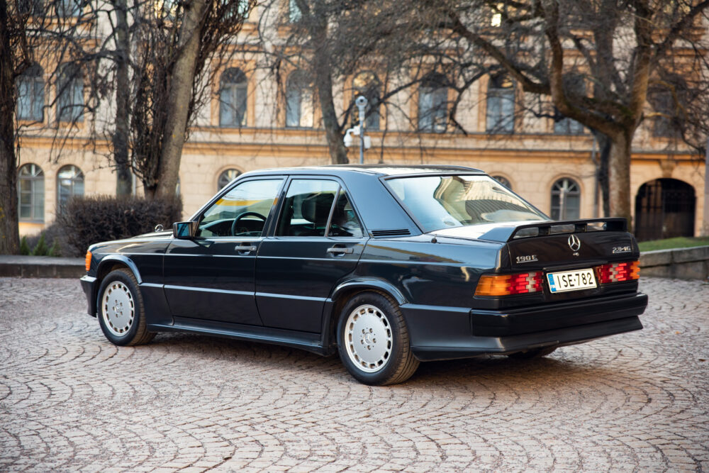 Vintage black Mercedes-Benz 190E parked on cobblestone street