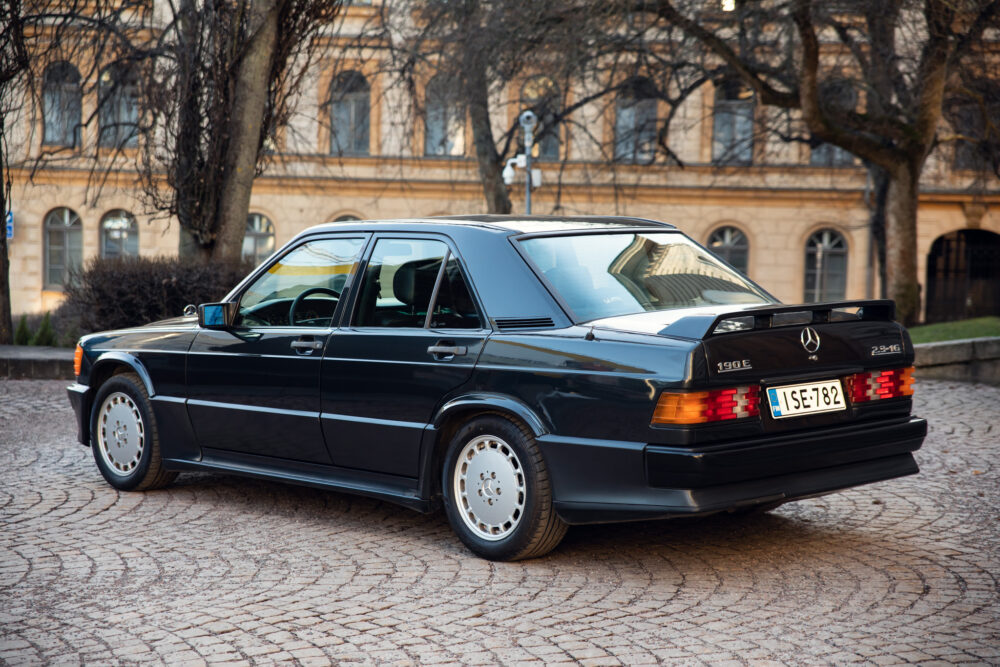 Vintage black Mercedes-Benz 190E parked on cobblestone street