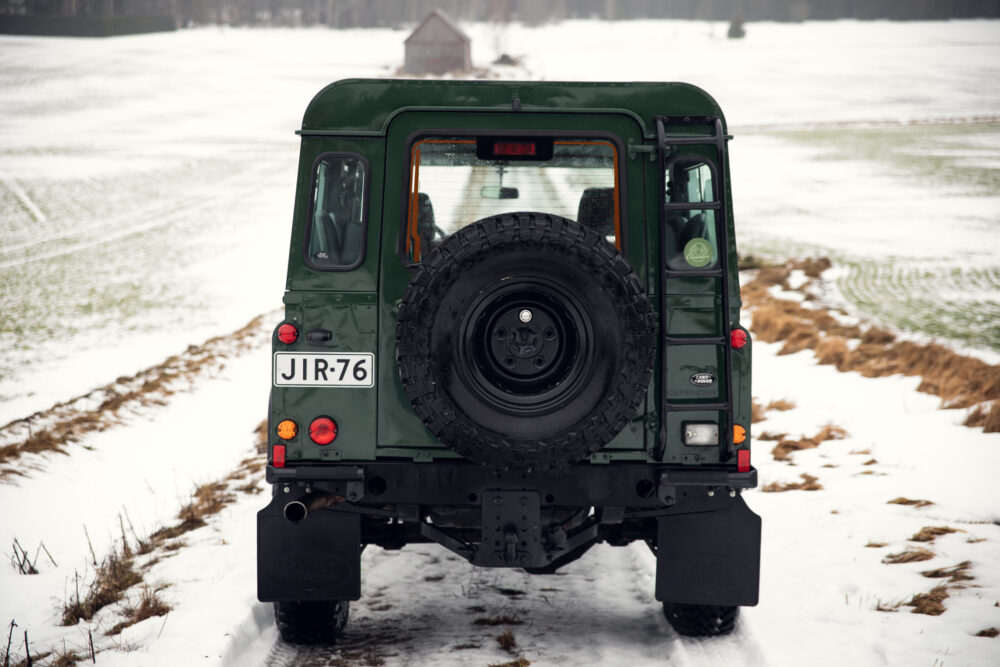 Green SUV on snowy field with spare tire mounted