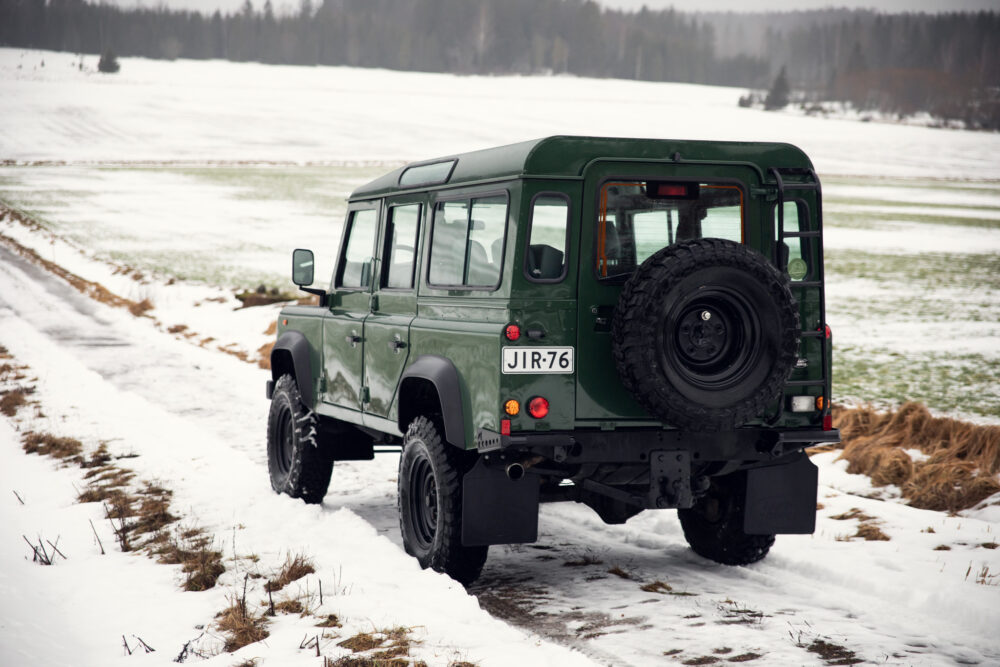 Green SUV traversing snowy rural landscape