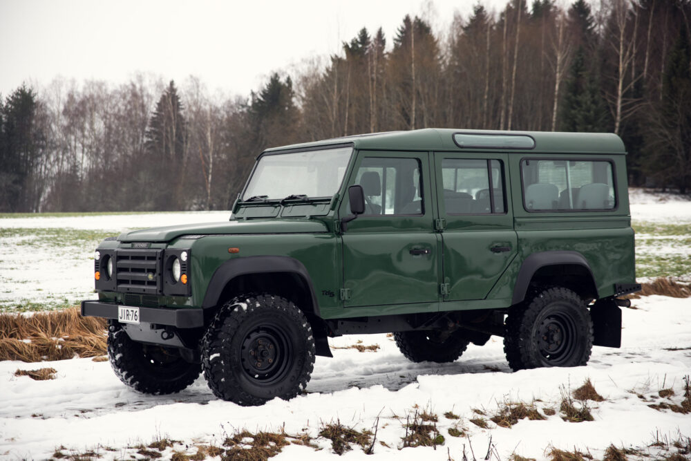 Green SUV on snowy field with trees