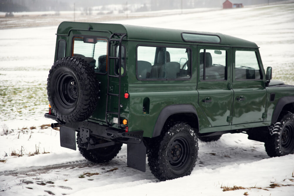 Green SUV on snowy field with spare tire mounted