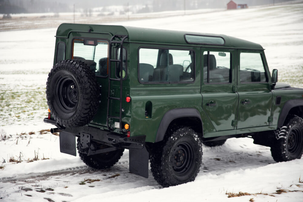 Green SUV on snowy field with spare tire mounted