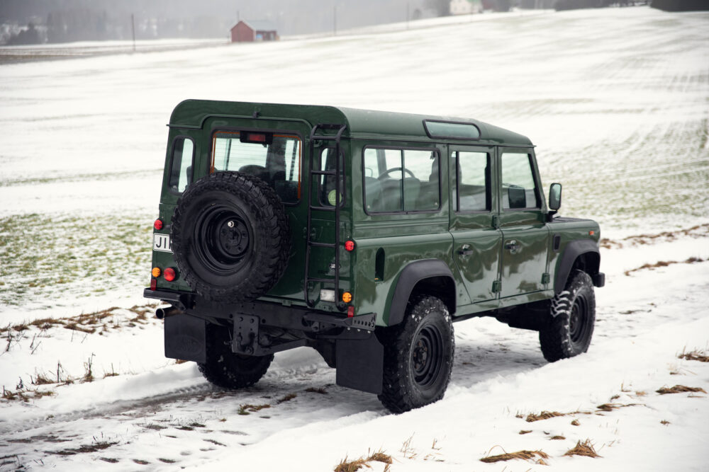 Green SUV on snowy field near barn