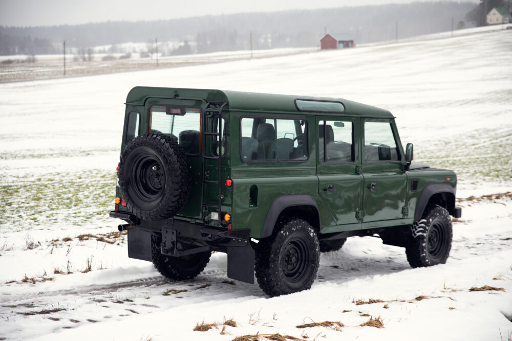 Green SUV on snowy field near barn