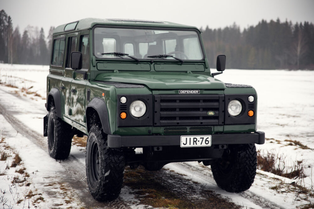 Green Land Rover Defender on snowy forest road