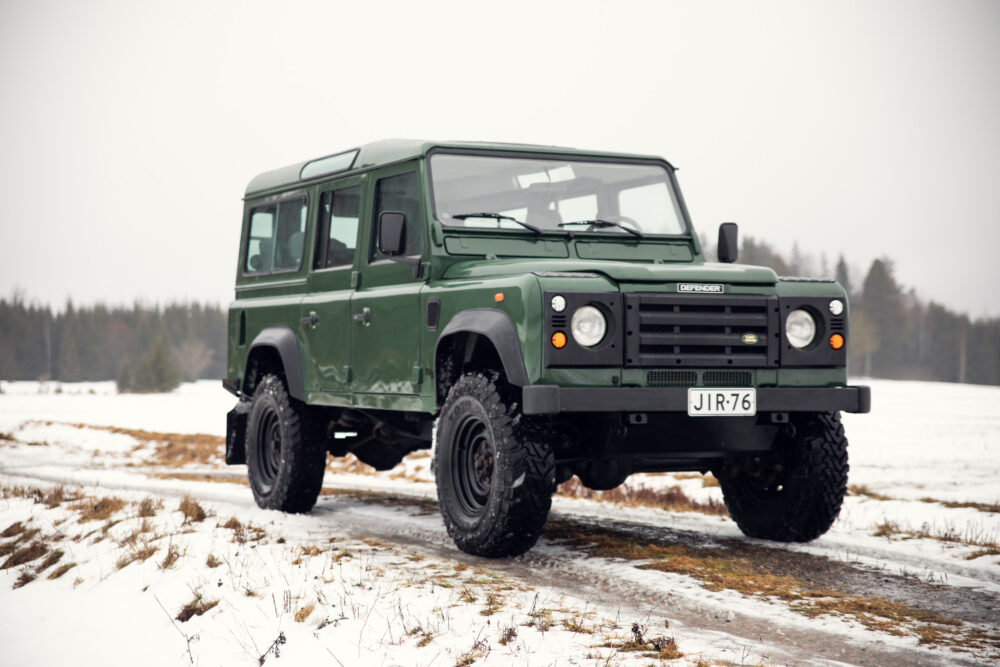 Green Land Rover Defender on snowy forest road