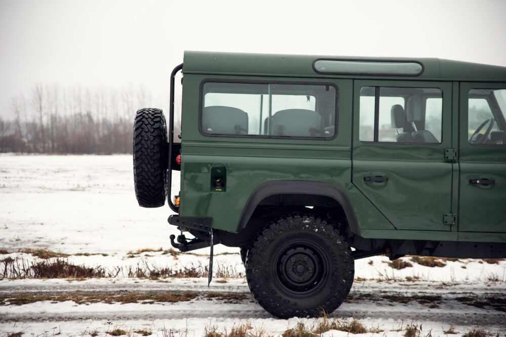 Green SUV on snowy field with spare tire mounted