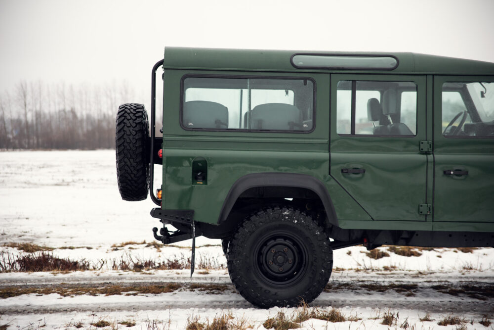 Green SUV on snowy field with spare tire mounted