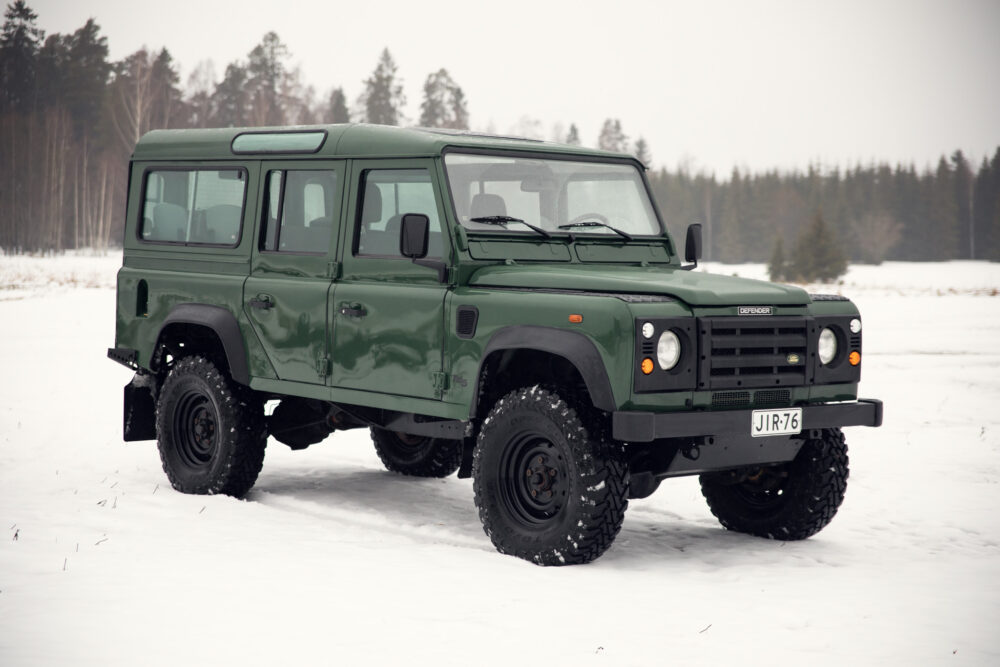 Green SUV on snowy forest ground