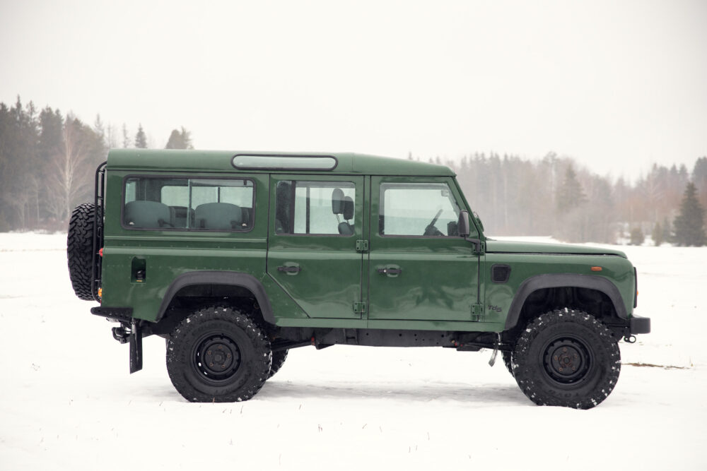 Green SUV on snowy field with trees