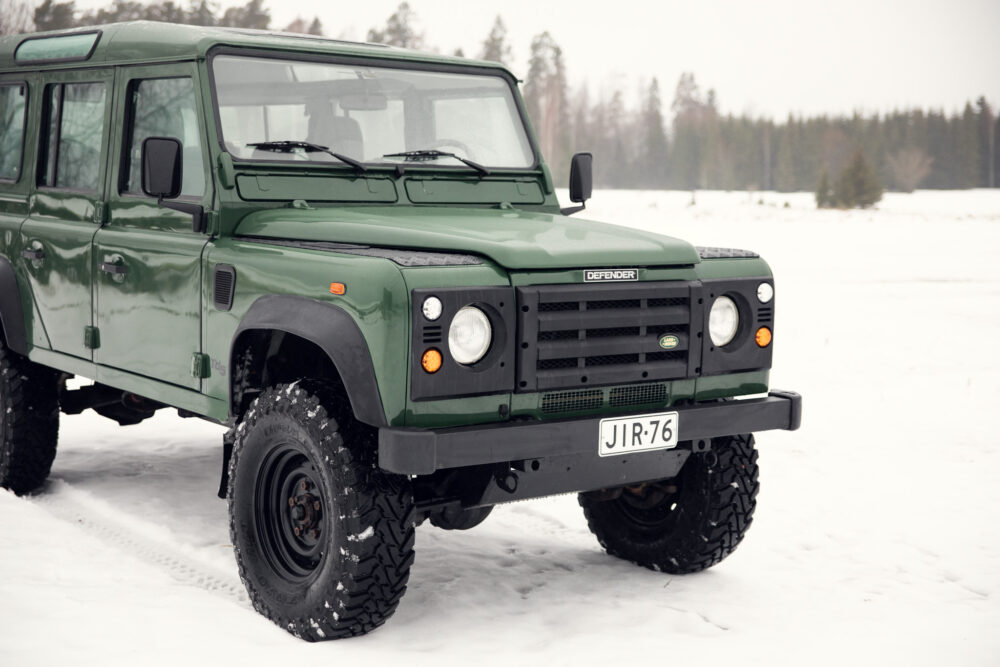 Green Land Rover Defender on snowy terrain