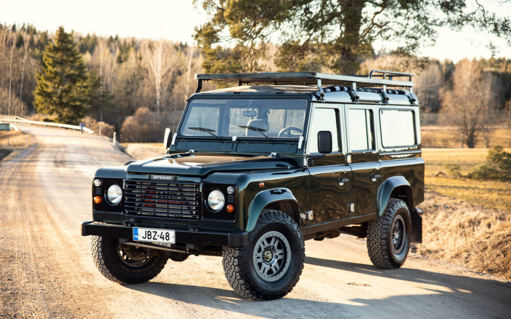 Green Land Rover Defender on rural road