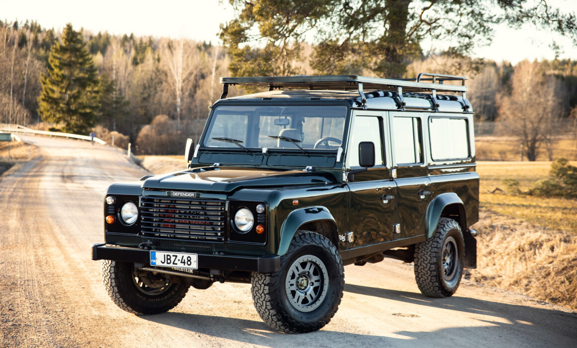 Green Land Rover Defender on rural road