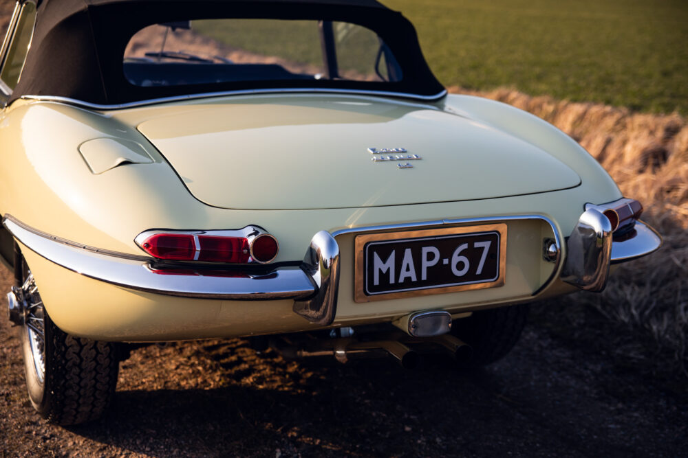 Vintage beige Jaguar E-Type rear view on field