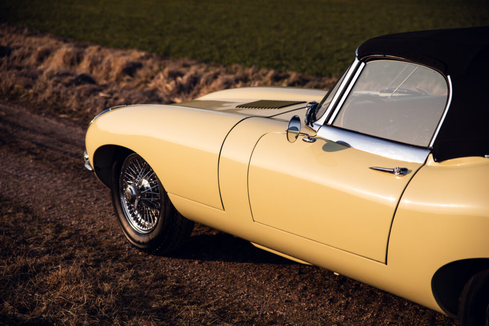 Yellow vintage convertible car parked beside field