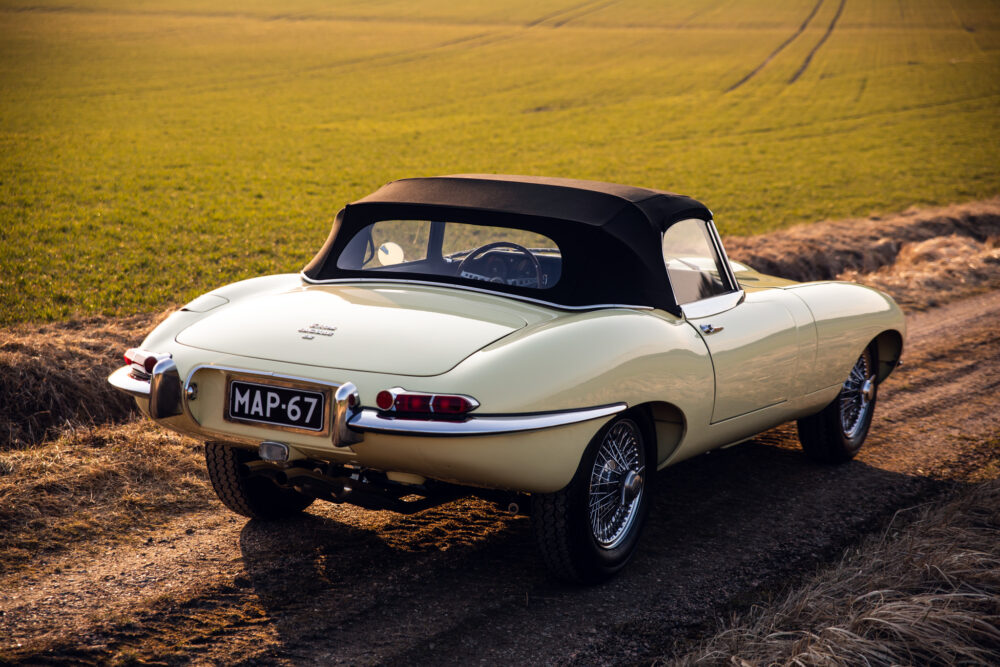 Vintage cream convertible car on country road at sunset