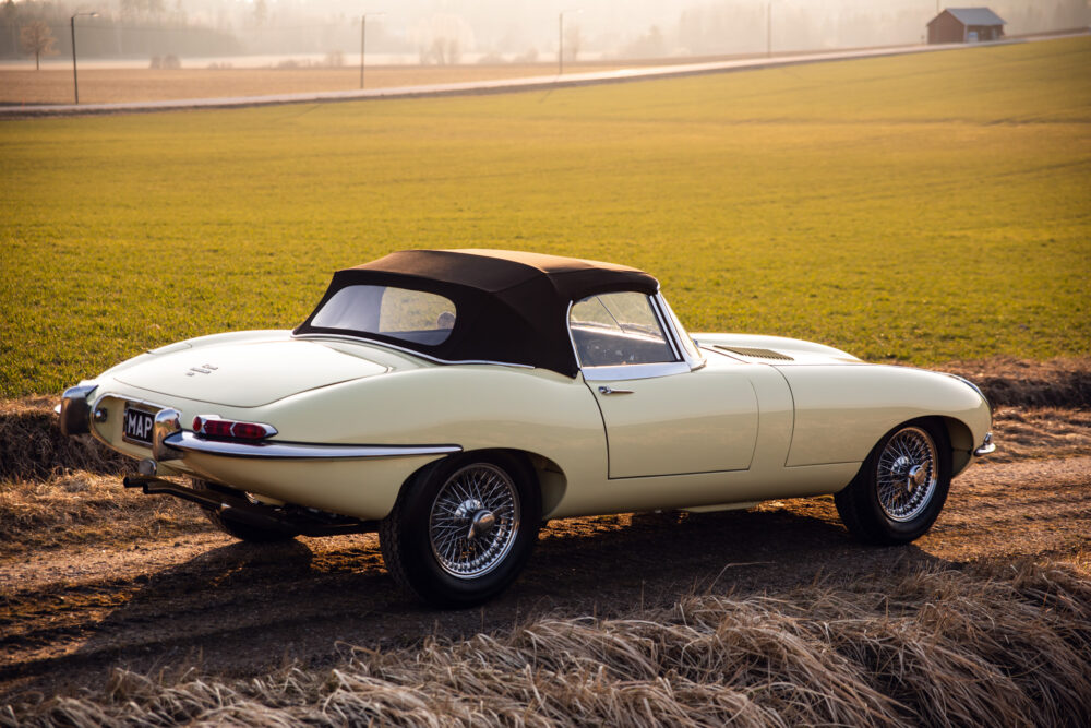 Vintage cream convertible car in rural field at sunset