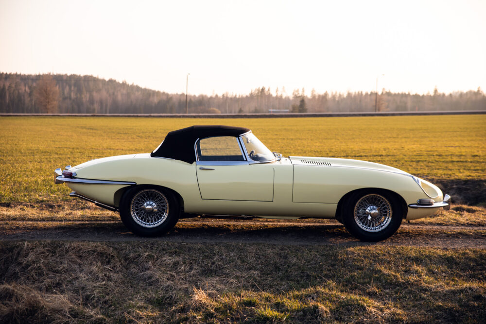 Vintage yellow convertible car in open field at sunset