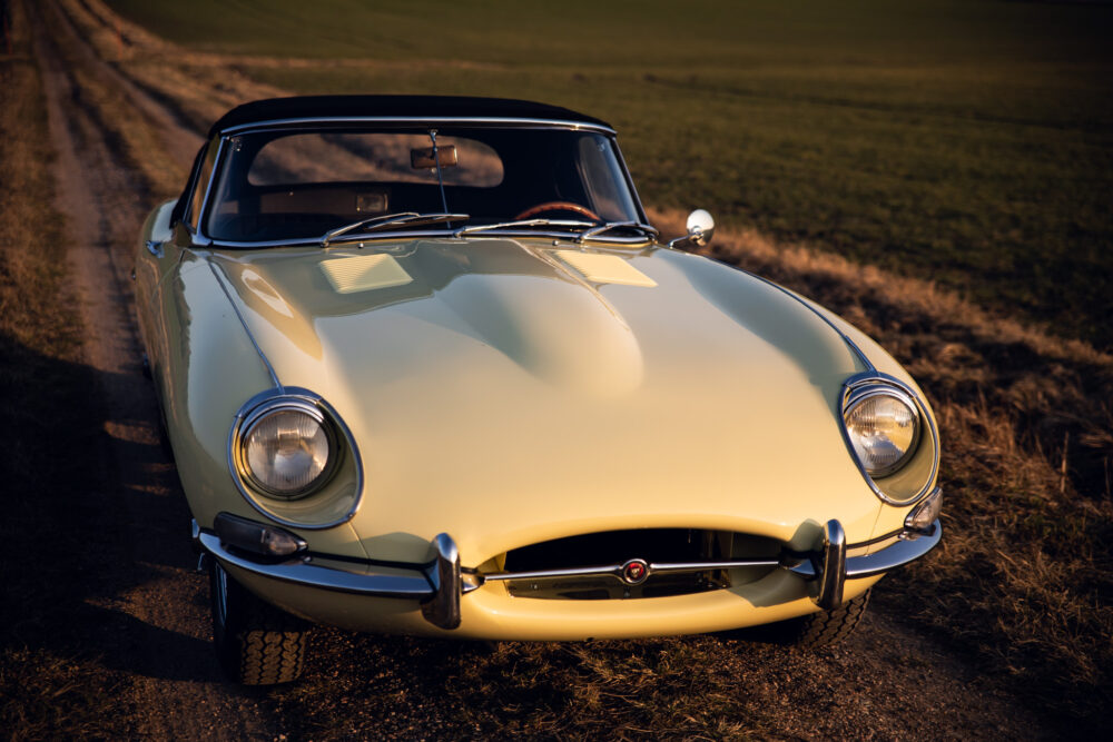 Vintage yellow sports car on rural road at sunset