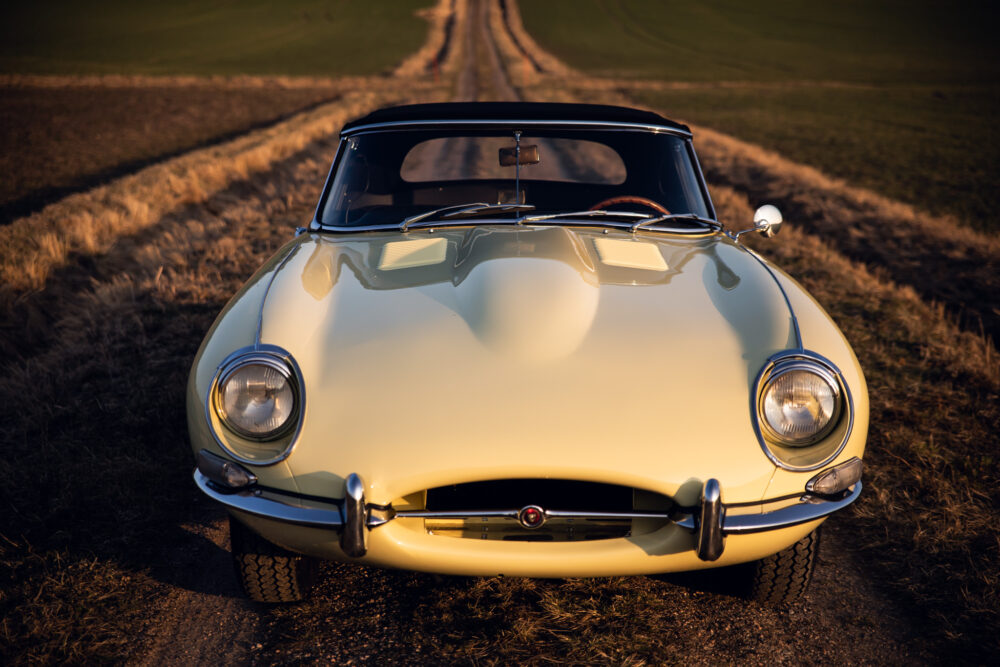 Vintage cream convertible car on country road at sunset