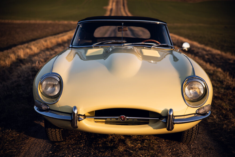 Vintage cream sports car on rural road at sunset