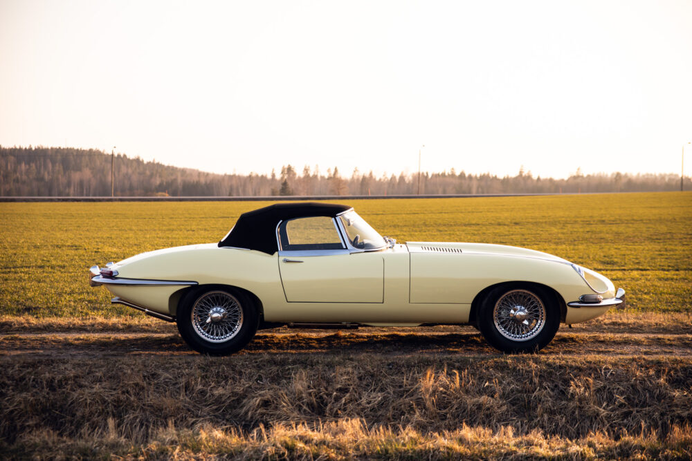 Vintage convertible car parked in open field at sunset